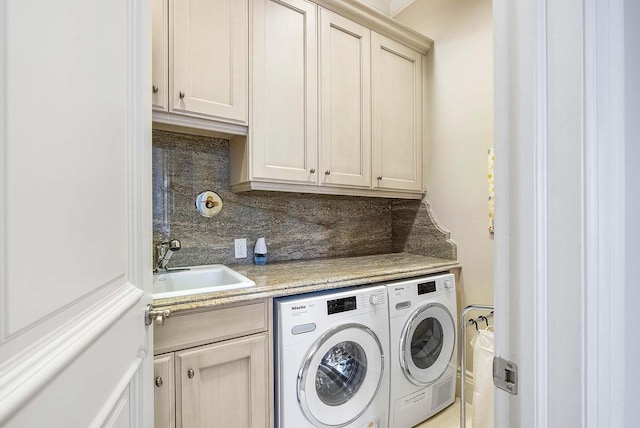 clothes washing area featuring cabinets, sink, and washer and dryer