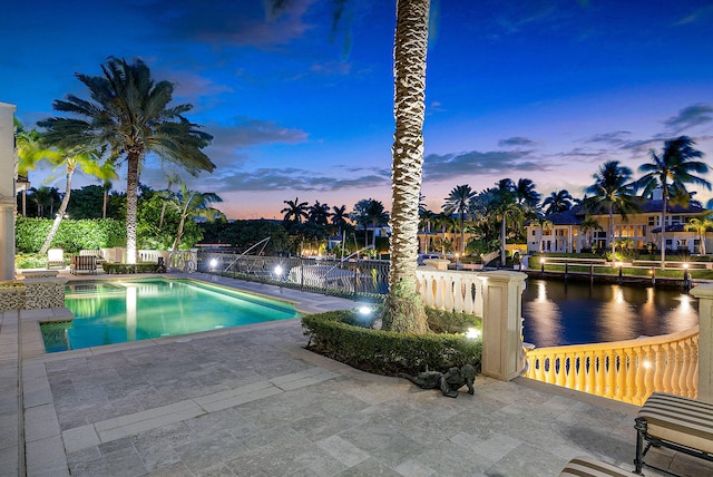 pool at dusk with a patio and a water view