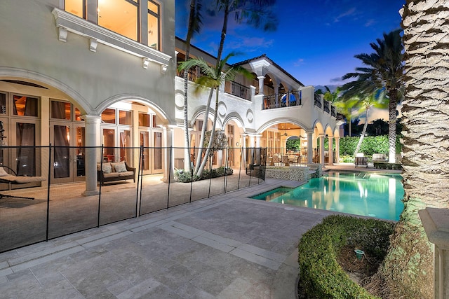 pool at dusk featuring french doors and a patio