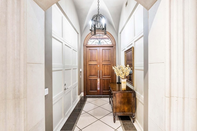 entryway with a notable chandelier, lofted ceiling, and light tile patterned floors