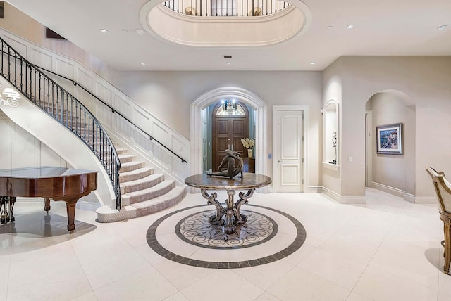 foyer entrance with a high ceiling, a tray ceiling, and light tile patterned floors