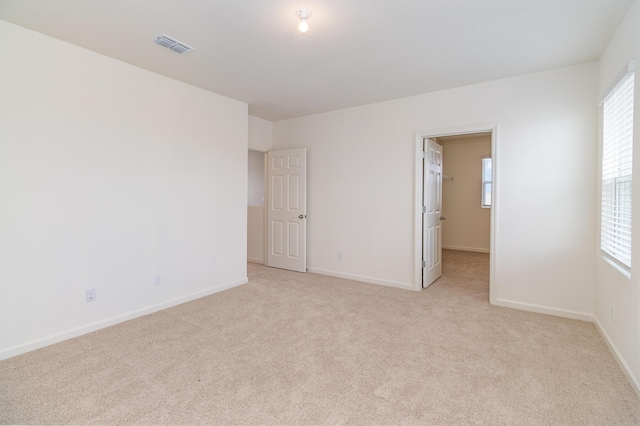 empty room featuring light colored carpet, baseboards, and visible vents