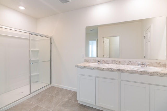 bathroom featuring a shower stall, tile patterned floors, double vanity, and a sink