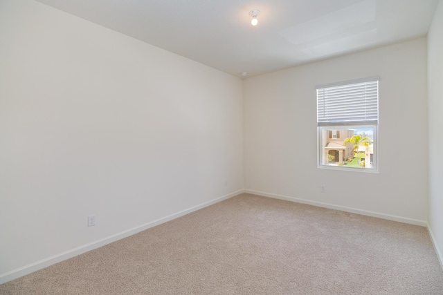 empty room featuring light carpet and baseboards