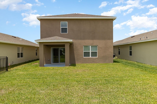 rear view of property with a lawn and stucco siding