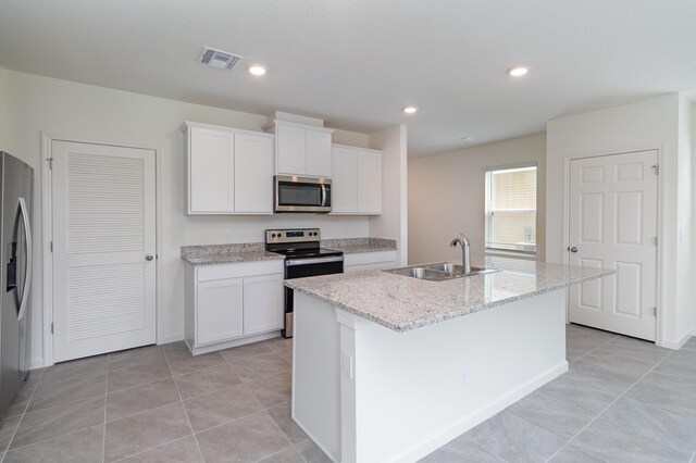 kitchen with white cabinetry, light tile patterned flooring, stainless steel appliances, sink, and a center island with sink