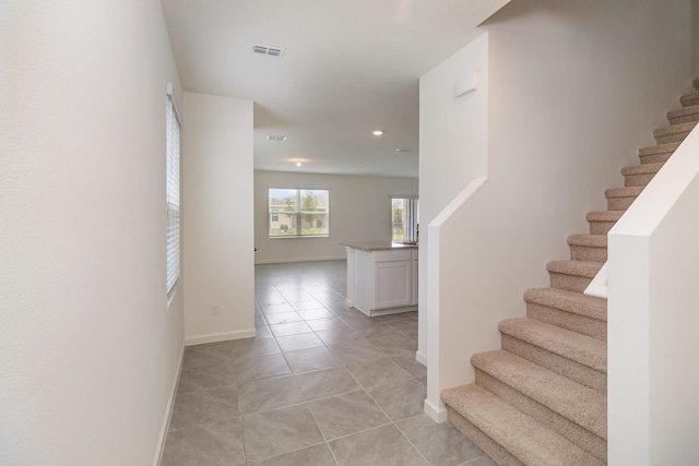 stairs featuring visible vents, baseboards, and tile patterned flooring