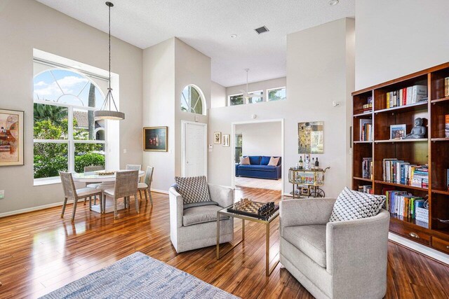 living room with hardwood / wood-style floors, a towering ceiling, and a textured ceiling