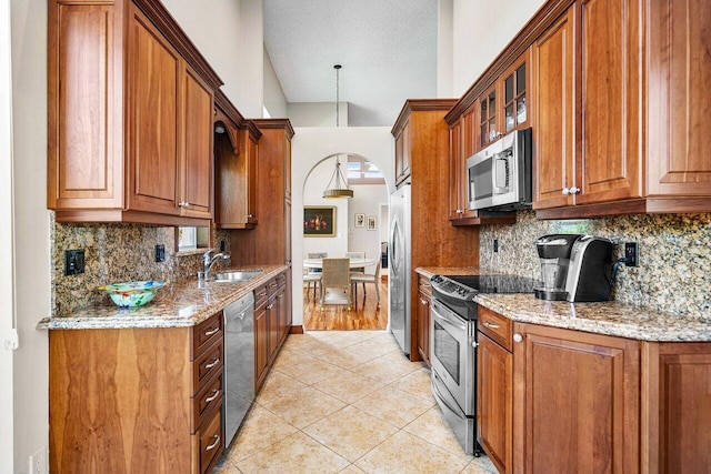 kitchen with light tile patterned floors, sink, appliances with stainless steel finishes, backsplash, and light stone countertops