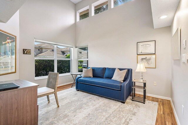 interior space with hardwood / wood-style flooring, a textured ceiling, and a towering ceiling