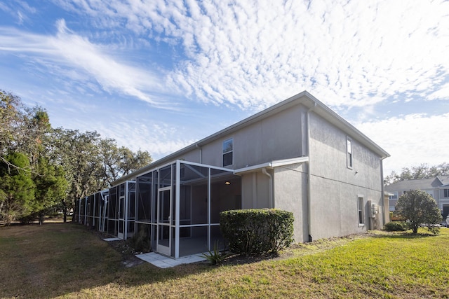 rear view of property featuring a lawn and glass enclosure