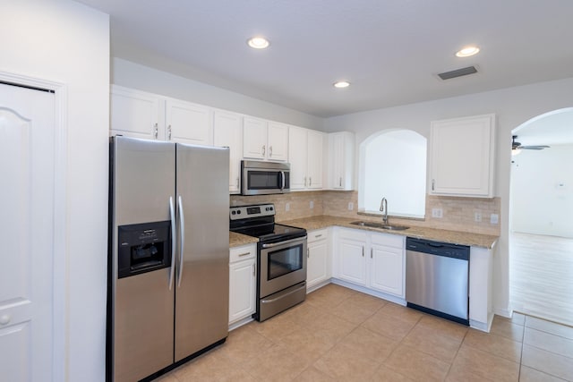 kitchen with decorative backsplash, stainless steel appliances, ceiling fan, sink, and white cabinets