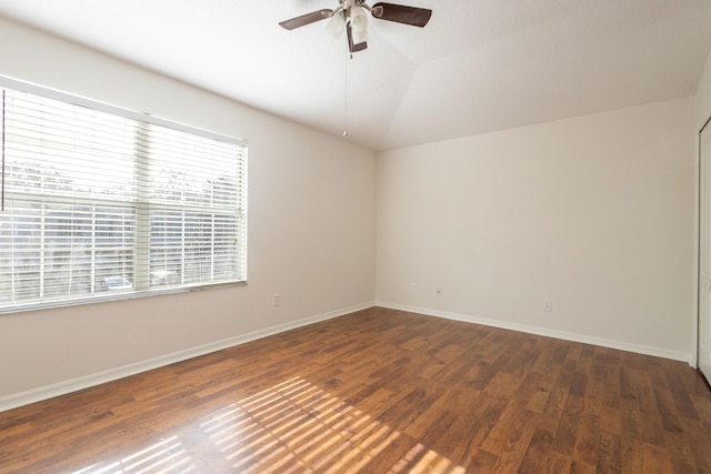 empty room with dark hardwood / wood-style floors, vaulted ceiling, and ceiling fan