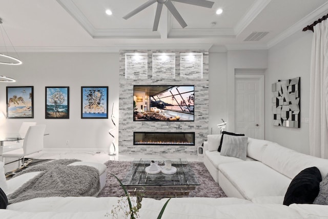 living room featuring ceiling fan, a large fireplace, ornamental molding, and a raised ceiling