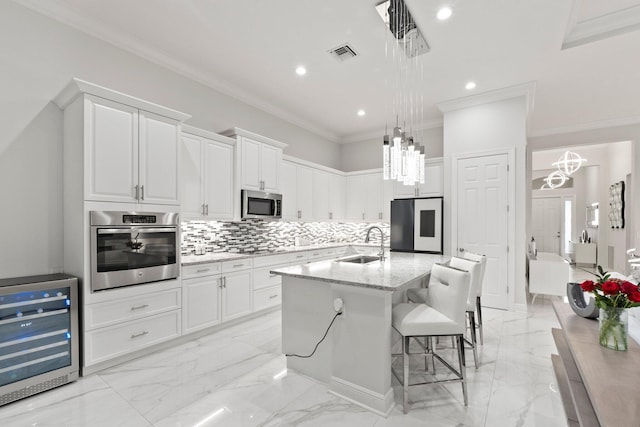 kitchen featuring sink, light stone countertops, wine cooler, appliances with stainless steel finishes, and a kitchen island with sink