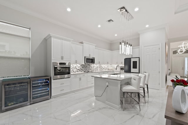 kitchen featuring sink, white cabinetry, pendant lighting, stainless steel appliances, and a kitchen island with sink