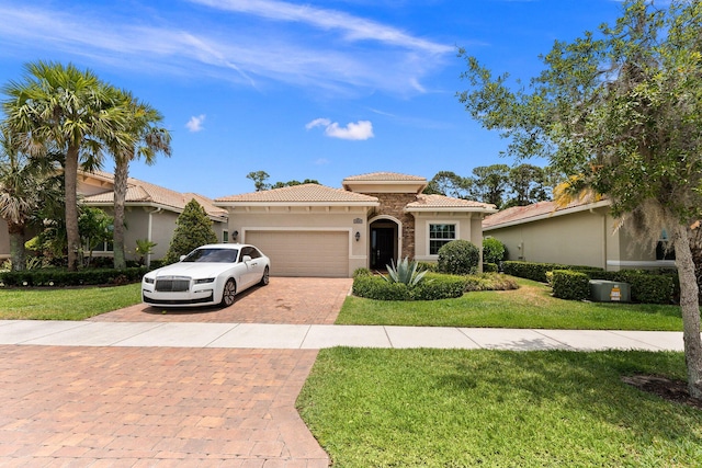 mediterranean / spanish home featuring a garage and a front lawn