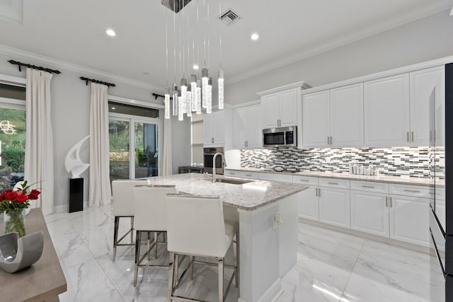 kitchen featuring white cabinetry, appliances with stainless steel finishes, sink, and a center island with sink