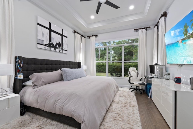 bedroom featuring ceiling fan, hardwood / wood-style floors, and a tray ceiling