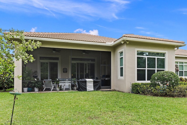 back of house featuring ceiling fan, a sunroom, and a lawn