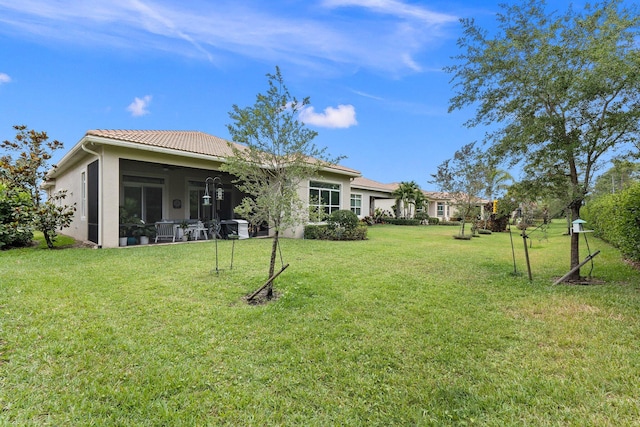 view of yard featuring a sunroom and ceiling fan