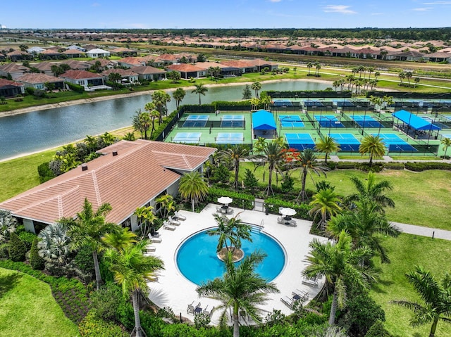 view of swimming pool featuring tennis court, a water view, and a yard