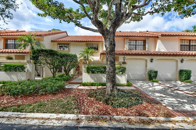 mediterranean / spanish home with fence, a tiled roof, stucco siding, an attached garage, and driveway