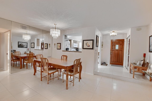dining area with visible vents, an inviting chandelier, a textured ceiling, and light tile patterned floors