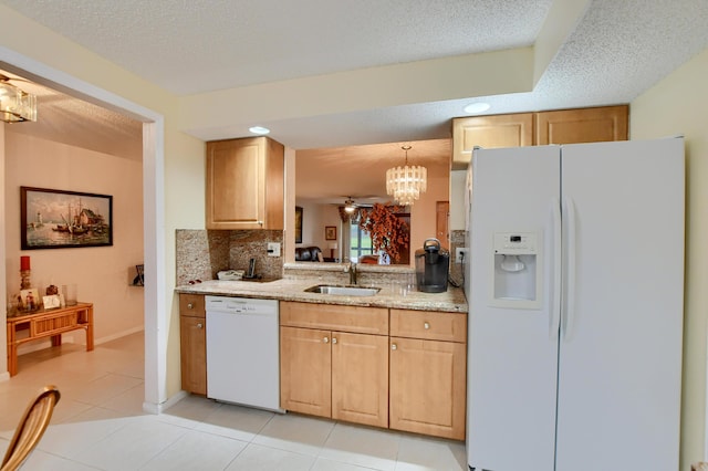 kitchen with a sink, light tile patterned flooring, white appliances, backsplash, and a notable chandelier