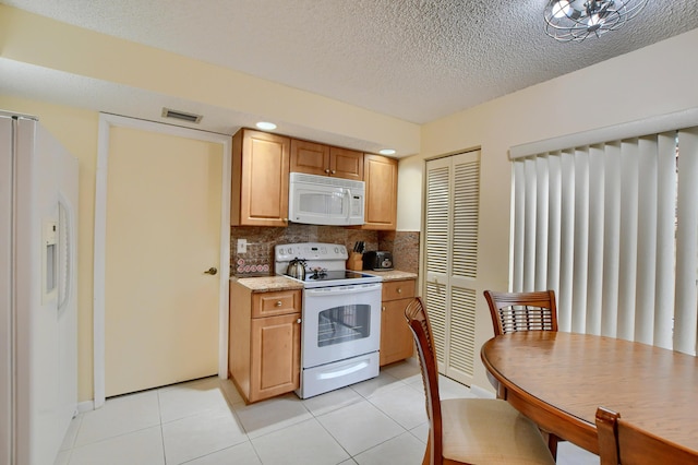 kitchen with decorative backsplash, visible vents, light tile patterned flooring, and white appliances