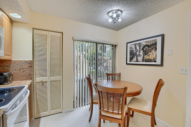 dining room featuring baseboards, a textured ceiling, and light tile patterned floors