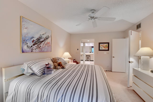 carpeted bedroom featuring a textured ceiling, ensuite bathroom, and ceiling fan