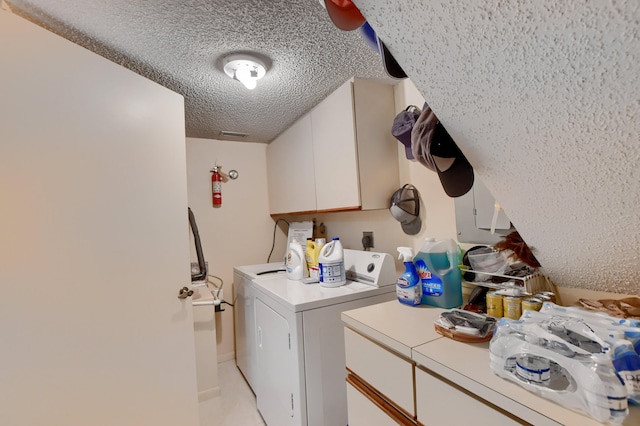 clothes washing area featuring cabinets, washing machine and dryer, and a textured ceiling