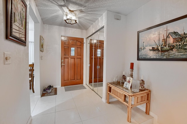 entryway with a textured ceiling, tile patterned floors, and baseboards