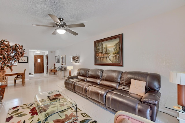 living room with a textured ceiling, ceiling fan, and light tile patterned floors