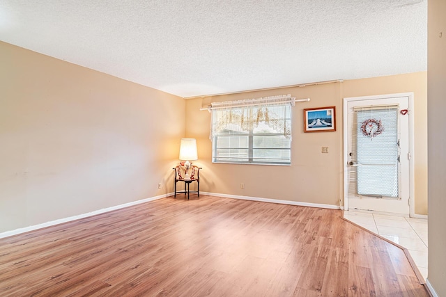 unfurnished room with a textured ceiling and light wood-type flooring