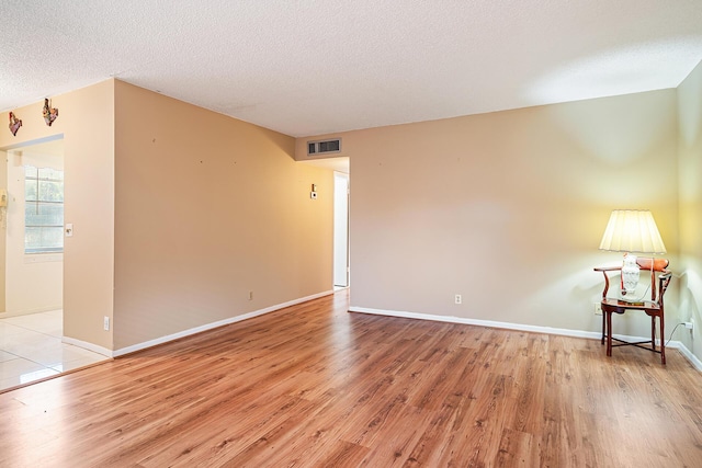 spare room featuring a textured ceiling and light hardwood / wood-style floors