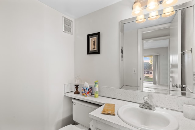 bathroom featuring vanity, toilet, and visible vents