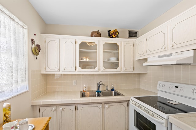 kitchen featuring tasteful backsplash, white range with electric stovetop, sink, and tile counters