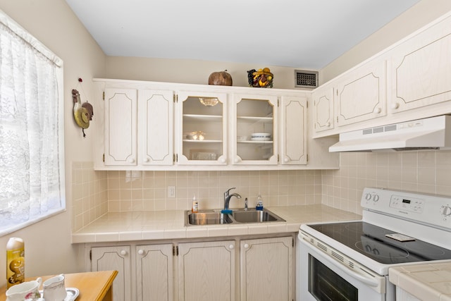 kitchen featuring visible vents, a sink, electric stove, under cabinet range hood, and tasteful backsplash