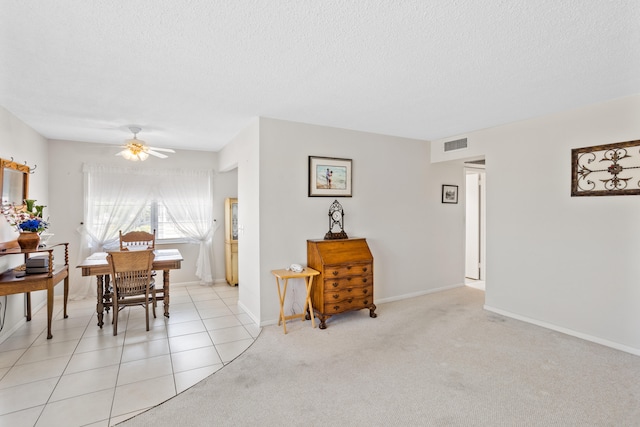 dining room featuring a textured ceiling, light colored carpet, and ceiling fan