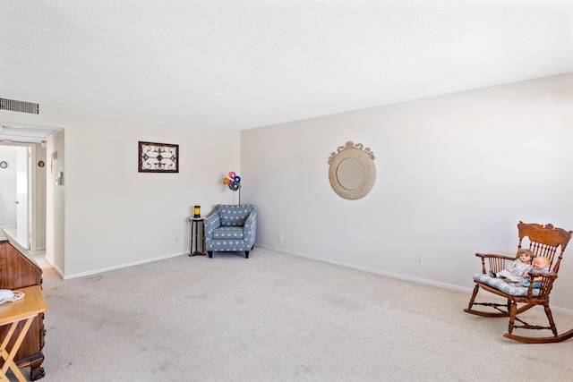 living area with visible vents, carpet flooring, a textured ceiling, and baseboards