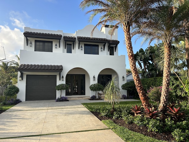 mediterranean / spanish home featuring a garage, concrete driveway, a tile roof, and stucco siding