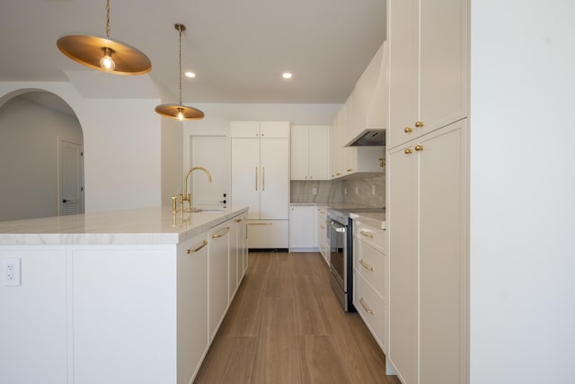 kitchen with stainless steel range with electric cooktop, sink, decorative light fixtures, white cabinetry, and decorative backsplash