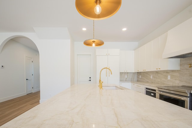 kitchen with sink, white cabinetry, decorative backsplash, hanging light fixtures, and stainless steel range with electric stovetop