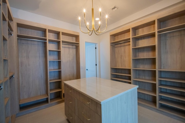 walk in closet featuring an inviting chandelier and light tile patterned floors