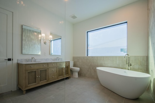 bathroom with vanity, tile patterned flooring, tile walls, and a tub to relax in