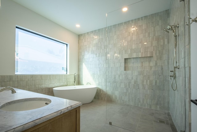 bathroom with tile walls, tile patterned flooring, separate shower and tub, and vanity