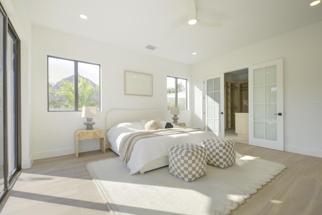 bedroom featuring french doors, ceiling fan, light hardwood / wood-style floors, and multiple windows