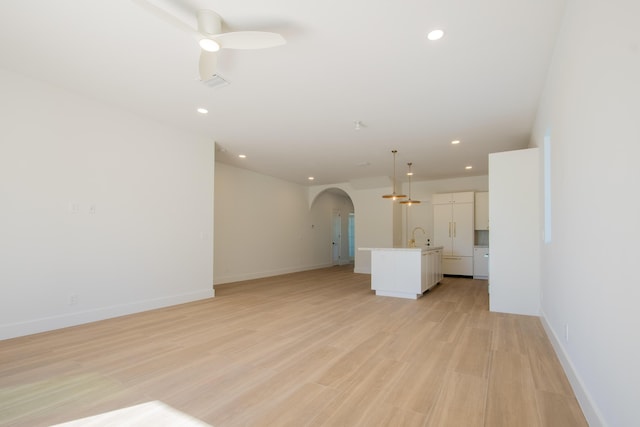 unfurnished living room featuring ceiling fan, light hardwood / wood-style flooring, and sink